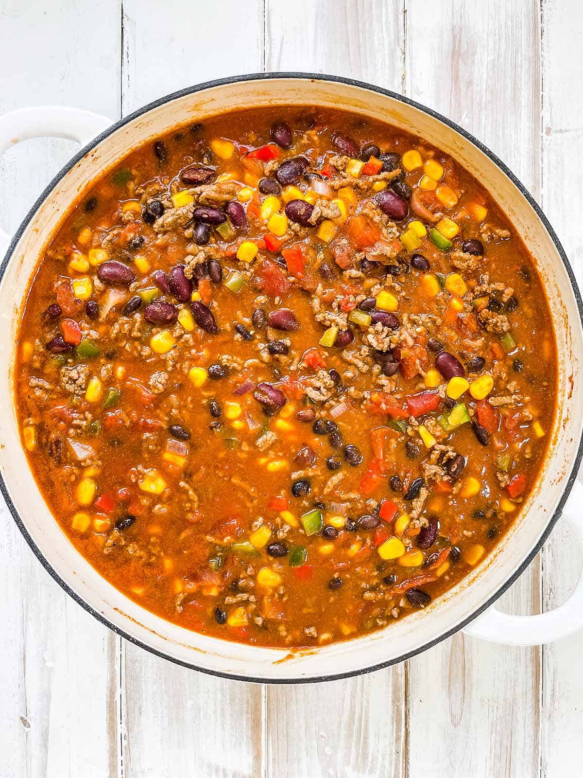 A skillet full of taco soup on a white wooden table.